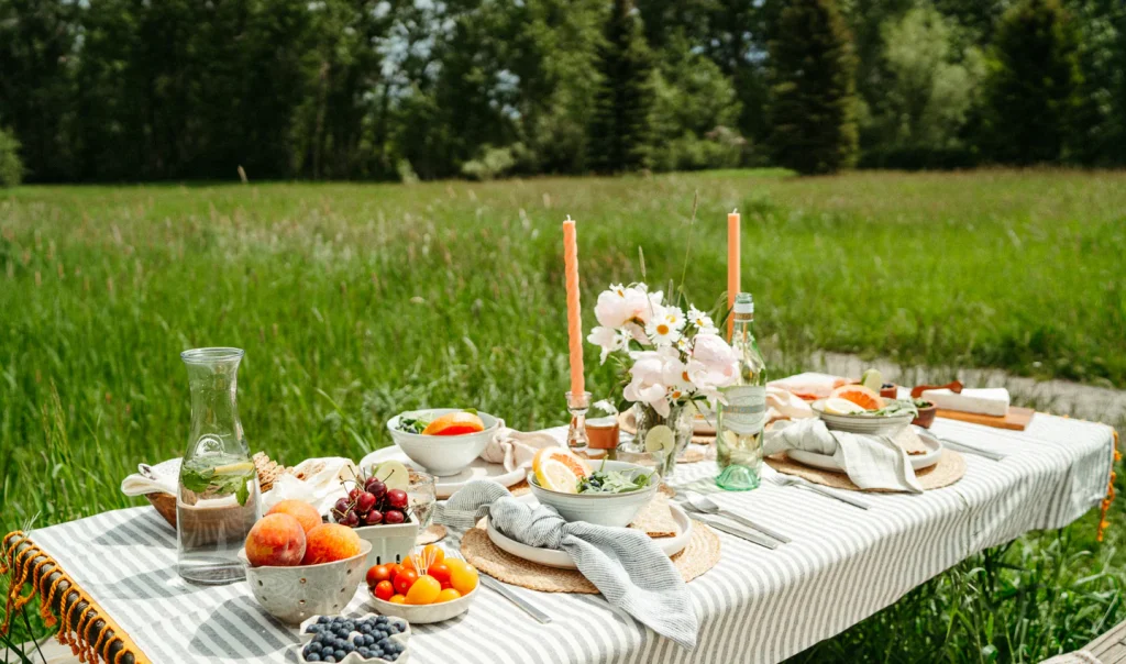 A spread of Tesco Finest summer product launches including savory pastel de nata, loaded carbonara dip, and warm Sicilian olives on a rustic outdoor table.