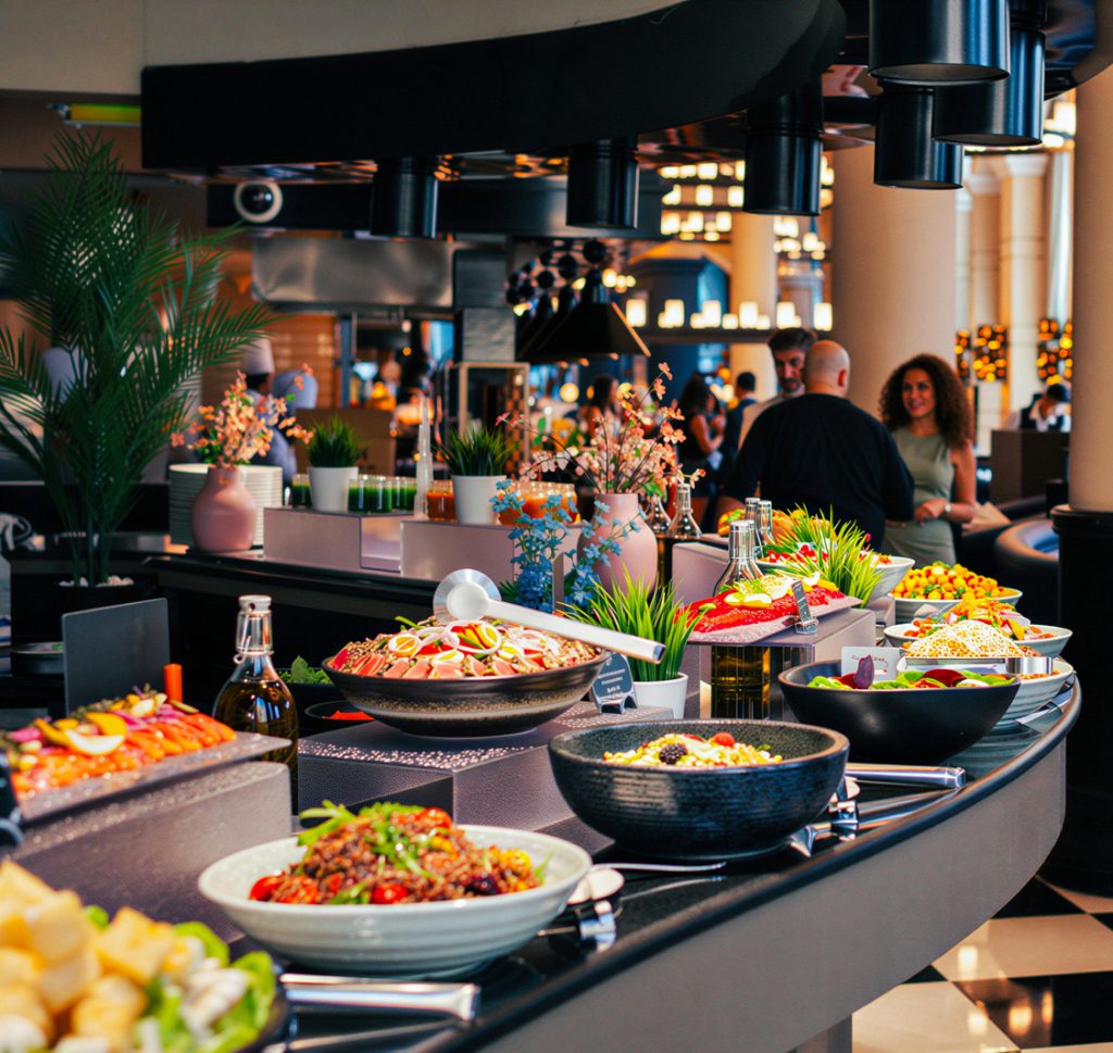 Modern UK restaurant dining room with servers presenting dishes to customers at a table.